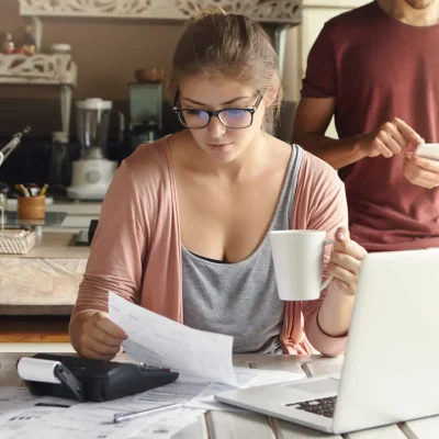 Jeune-femme-race-blanche-concentree-ayant-cafe-du-matin-tout-travaillant-finances-dans-cuisine